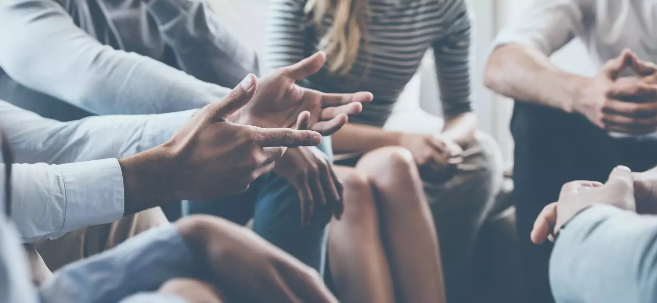 Close-up of people communicating while sitting in circle and gesturing