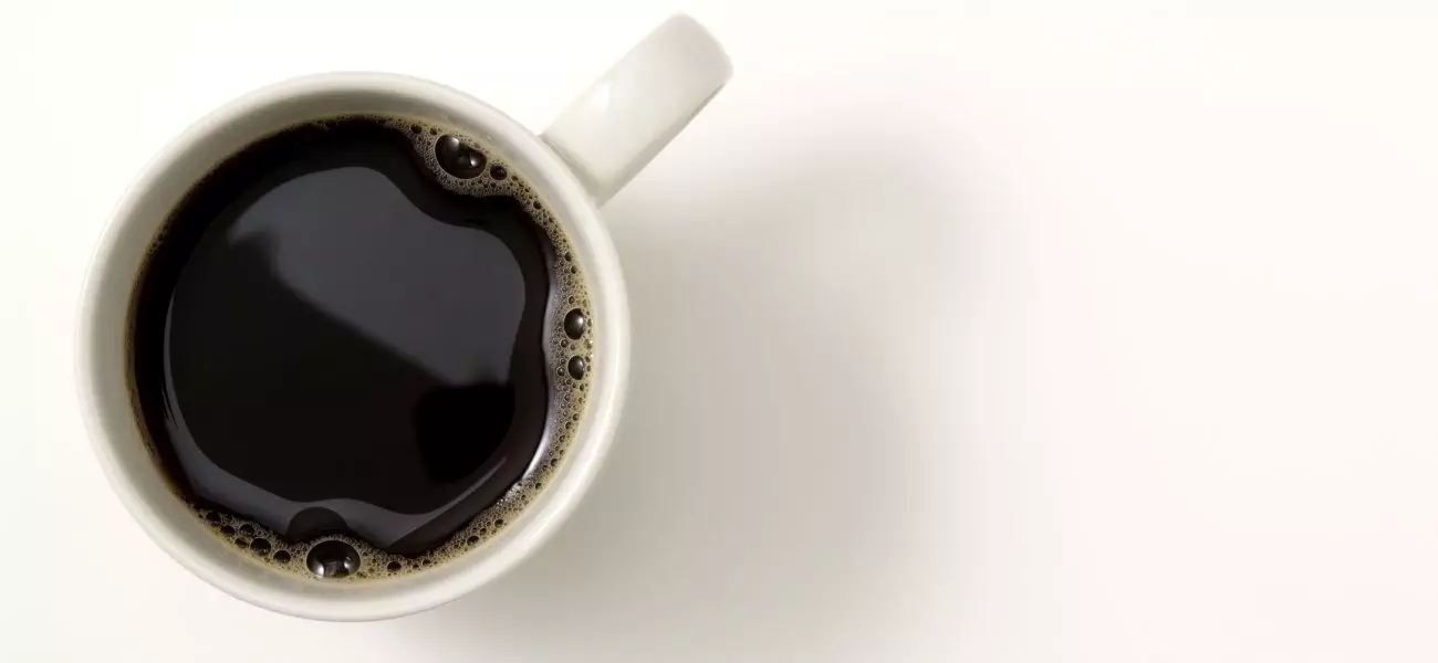 Overhead shot of a cup of coffee isolated on white background with soft shadow.