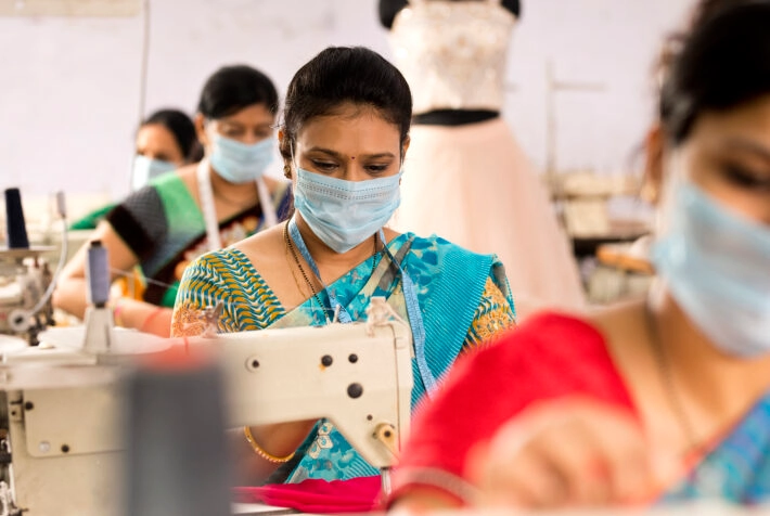Indian woman textile workers with protective face mask on production line