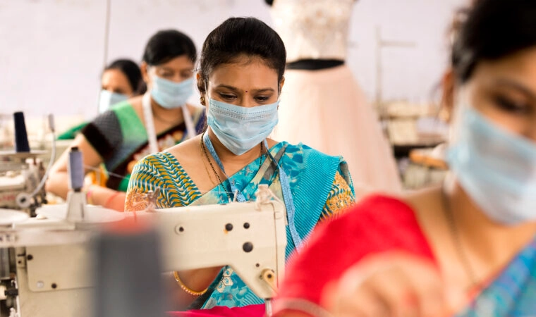 Indian woman textile workers with protective face mask on production line