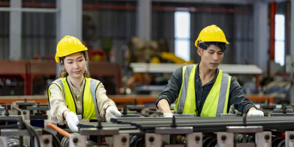 Team of Asian industrial worker is checking the setup value of metal sheet roll forming machine inside roof factory for safety industry construction concept